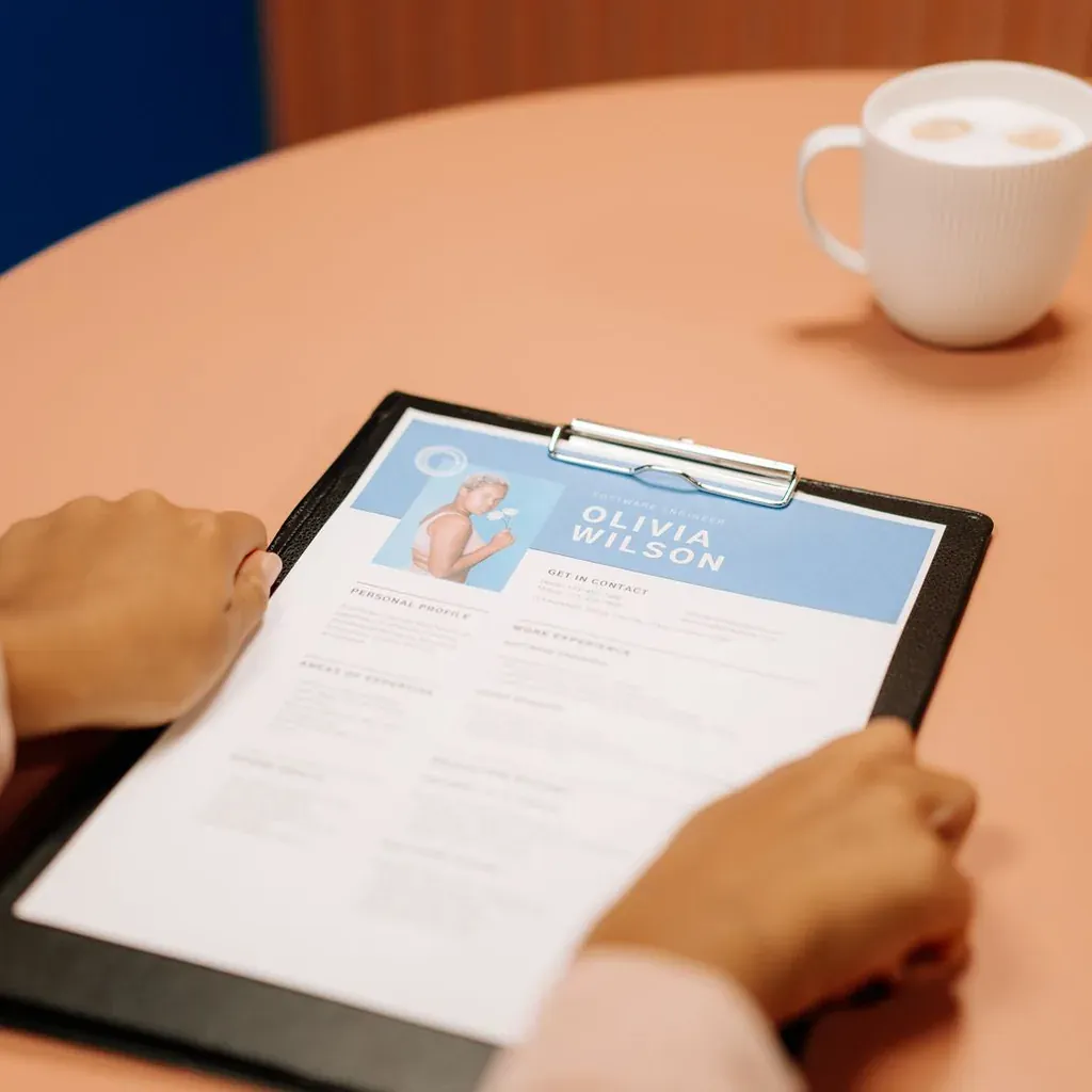 A person reviewing a software engineer resume on a clipboard at a cafe table